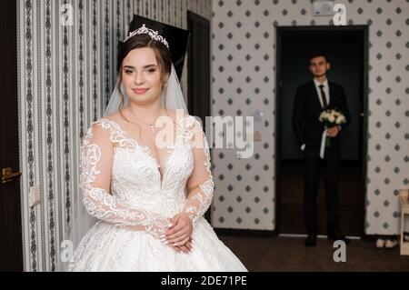 le marié rencontre la mariée et donne un bouquet de fleurs dans la chambre d'hôtel Banque D'Images