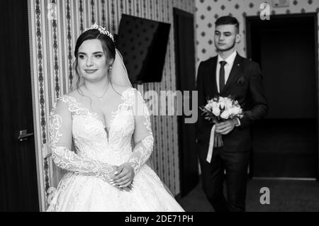 le marié rencontre la mariée et donne un bouquet de fleurs dans la chambre d'hôtel Banque D'Images