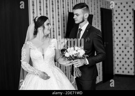 le marié rencontre la mariée et donne un bouquet de fleurs dans la chambre d'hôtel Banque D'Images