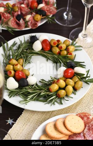 Un hors-d'œuvre de romarin farci d'olives avec de la mozzarella et des tomates cerises. Fait sous forme de couronne de Noël. Banque D'Images