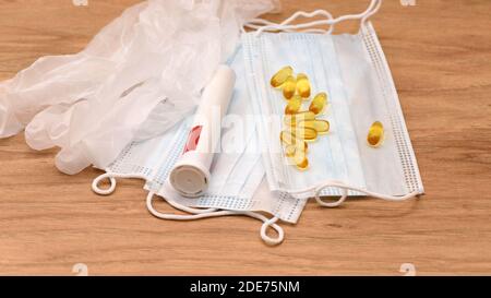 Masques médicaux de protection contre les virus, pilules jaunes et contenant en plastique sur une surface en bois. Kit médical pour la protection contre le COVID-19 et pour les soins de santé. Banque D'Images