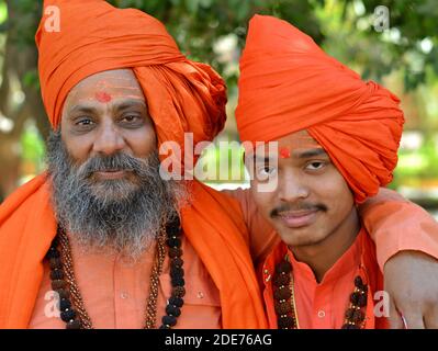 Deux hommes hindous indiens saints (Saivite sadhus, moines, dévotés), vieux et jeunes, portent des tenues orange et se posent ensemble pendant Maha Shivaratri. Banque D'Images