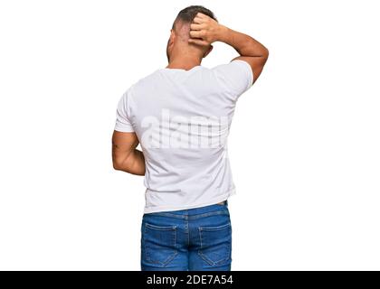 Beau muscle homme portant décontracté t-shirt blanc en arrière de penser doute avec main sur la tête Banque D'Images