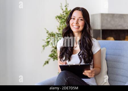 Portrait d'une jeune femme au bureau. La femme écrit des données dans le questionnaire Banque D'Images