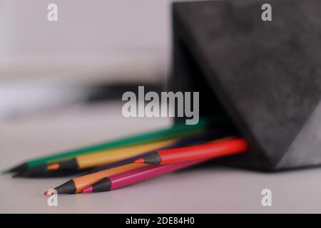 Un gros plan de crayons dans un coffret en béton. Couleurs. Sur une table blanche Banque D'Images