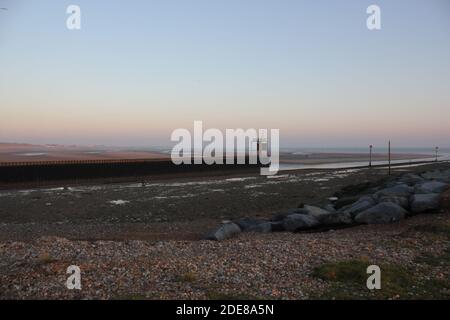 Pett Level Beach au coucher du soleil. Avec piscine d'eau de mer et rochers en premier plan. Winchelsea Beach rencontre les falaises une forêt pétrifiée visible à basse altitude Banque D'Images