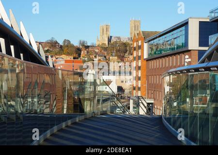 Vue sur la colline escarpée et la cathédrale depuis la nouvelle passerelle controversée de Brayford montrant les bâtiments reflétés par les côtés miroirs du pont Banque D'Images