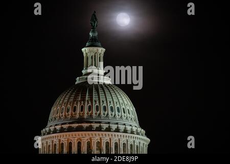 Washington, États-Unis. 29 novembre 2020. Une pleine lune s'élève derrière le Capitole des États-Unis à Washington, DC, le 29 novembre 2020, dans le contexte de la pandémie du coronavirus. Bien qu'obscurcie par des nuages de lumière, la pleine lune de novembre 29-30 était accompagnée d'une éclipse lunaire pénombre, ce qui a causé l'apparition d'une lune légèrement plus sombre. (Graeme Sloan/Sipa USA) Credit: SIPA USA/Alay Live News Banque D'Images