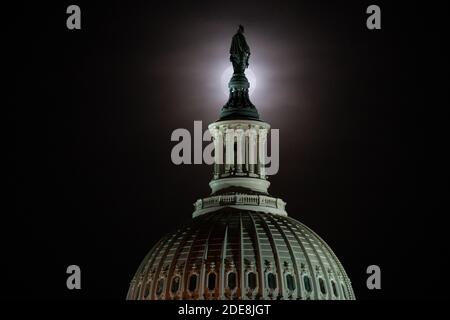 Washington, États-Unis. 29 novembre 2020. Une pleine lune s'élève derrière le Capitole des États-Unis à Washington, DC, le 29 novembre 2020, dans le contexte de la pandémie du coronavirus. Bien qu'obscurcie par des nuages de lumière, la pleine lune de novembre 29-30 était accompagnée d'une éclipse lunaire pénombre, ce qui a causé l'apparition d'une lune légèrement plus sombre. (Graeme Sloan/Sipa USA) Credit: SIPA USA/Alay Live News Banque D'Images