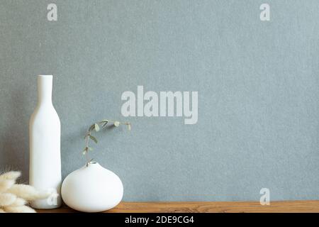Décoration intérieure. Vase en céramique avec plante sèche sur table en bois. Fond vert kaki Banque D'Images