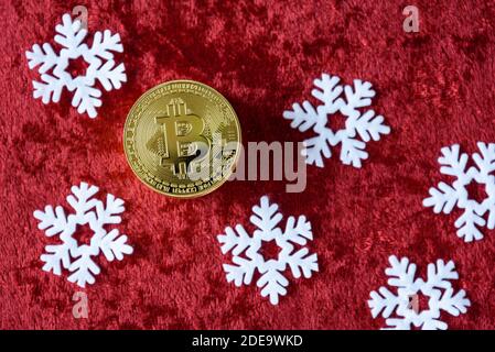 Pile de bitcoins d'or sur fond de velours rouge, avec flocons de neige blancs Banque D'Images