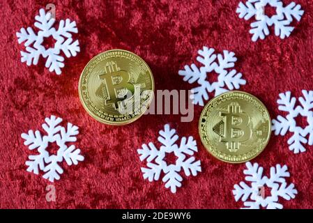 Pile de bitcoins d'or sur fond de velours rouge, avec flocons de neige blancs Banque D'Images