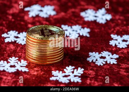 Pile de bitcoins d'or sur fond de velours rouge, avec flocons de neige blancs Banque D'Images