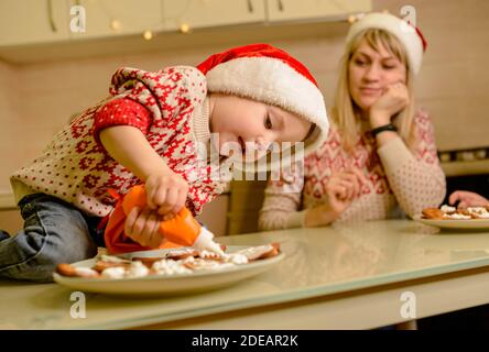 Père Noël enfant faisant des biscuits pour la famille dans la cuisine confortable. Aide du père Noël Banque D'Images