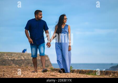 En tenant les mains et en marchant tranquillement vers l'avant en regardant la mer dans le chemin de Galle fort, un jeune couple enceinte se détendant le soir, soleil Banque D'Images