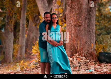 Belle enceinte jeune couple sous l'ombre des arbres soir, tenant sur les autres debout, doux et attentionné parents s'attendant à un enfant conce Banque D'Images