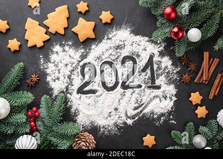 Nouvel an 2021, composition de Noël avec biscuits, sapin et nombre écrit sur la farine sur fond de tableau noir Banque D'Images
