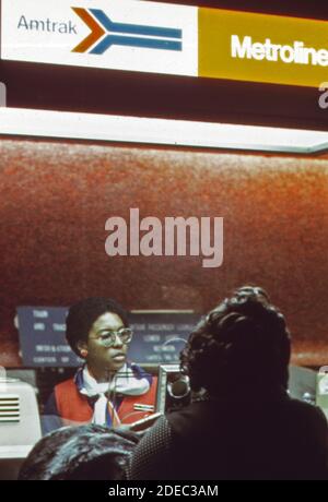 Les passagers se trouvent à un comptoir de billetterie Amtrak de la gare Penn de New York (Pennsylvania Station) pour acheter un billet sur le metroliner. CA. 1974 Banque D'Images