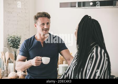 Heureux couple interracial parlant ensemble avoir un bon moment à à la maison le matin Banque D'Images