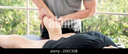 Thérapeute masculin offrant un massage des jambes et du mollet au patient d'athlète sur le lit en clinique, concept de physiothérapie sportive Banque D'Images