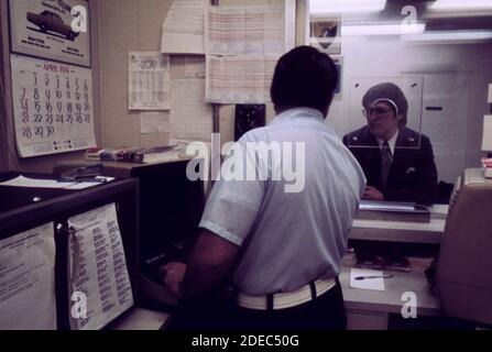 L'agent de billetterie Amtrak répond à une question pour un client à une gare dans une banlieue proche de Washington D.C. ca. 1974 Banque D'Images