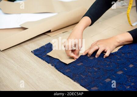 Le concepteur fait passer le motif de papier sur le tissu à la table confection de la robe dans une boutique sur mesure Banque D'Images