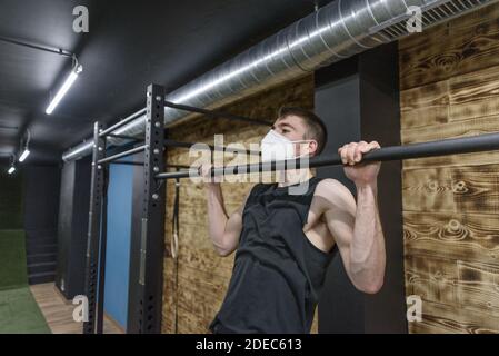 Un homme caucasien en forme faisant des pull-ups dans la salle de gym Banque D'Images