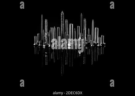 Ville nocturne de vis, boulons et écrous avec réflexion sur fond noir. L'idée de la publicité de photos de fixations. Installation industrielle Banque D'Images