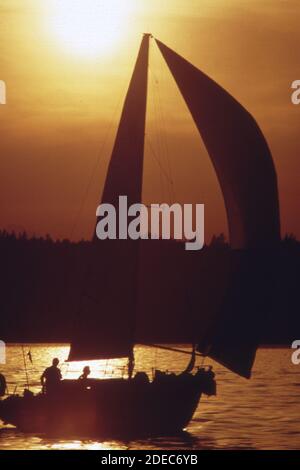 Photo des années 1970 (1973) - course en voilier en soirée par les membres du club de bateaux de Tacoma sur Puget Sound. La brise est très légère ; le spinnaker tire profit de chaque bouffée Banque D'Images
