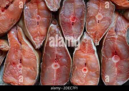 Des tranches de poisson rouge sont disposées en rangée. Résumé du saumon kéta ou saumon rose en gros plan. Toile de fond pour les produits du poisson Banque D'Images