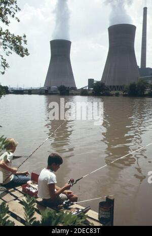 Photo des années 1970 (1973) - les garçons pêchent dans la rivière Kanawha à PoCA. Sur la rive opposée, la vapeur s'élève des tours de refroidissement d'eau de la centrale électrique John Amos Banque D'Images