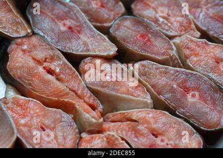Des tranches de poisson rouge sont disposées en rangée. Résumé du saumon kéta ou saumon rose en gros plan. Toile de fond pour les produits du poisson Banque D'Images