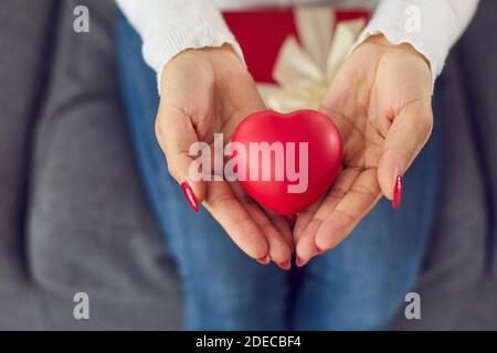 Gros plan des mains de la femme tenant le cœur rouge comme symbole de Partager l'amour et offrir des cadeaux de Saint-Valentin Banque D'Images