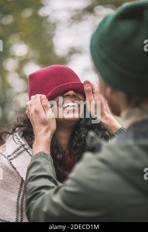 Homme touchant un chapeau sur la tête des femmes Banque D'Images