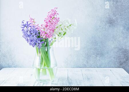 Fond floral printanier. Bouquet de fleurs de tulipe violet, rose, blanc sur l'étagère devant le mur de pierre - image Banque D'Images