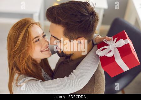 Un jeune couple aimant se serre et se regarde l'un l'autre pendant offrir des cadeaux et célébrer les fêtes Banque D'Images