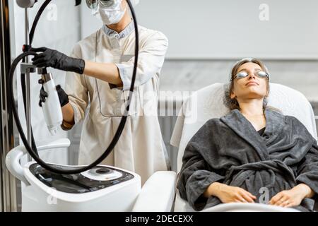 Jeune femme se préparant à un traitement de rajeunissement au spa médical bureau avec un médecin en arrière-plan Banque D'Images
