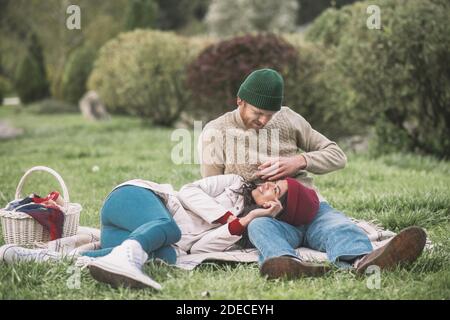 Un jeune couple se rafraîchil sur l'herbe pendant le pique-nique Banque D'Images