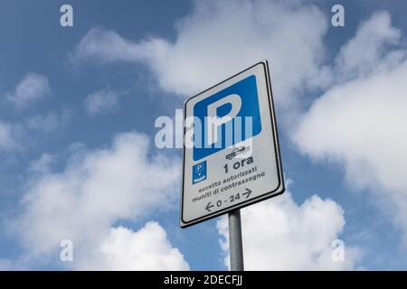 Panneau de stationnement avec limite de temps d'une heure sauf autorisation, isolé sur un ciel bleu avec des nuages blancs. Banque D'Images