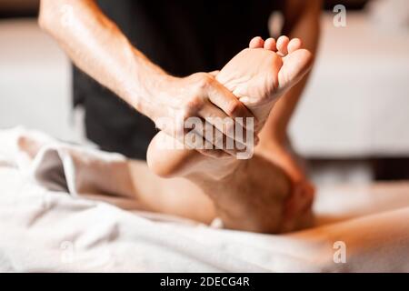 Thérapeute professionnel effectuant un massage profond à un client masculin au Spa salon. Travail à pied, gros plan Banque D'Images