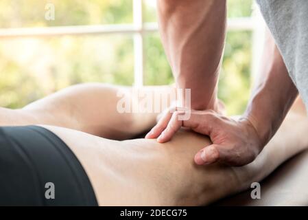 Thérapeute masculin offrant un massage des jambes et du mollet au patient d'athlète sur le lit en clinique, concept de physiothérapie sportive Banque D'Images