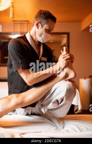 Thérapeute professionnel effectuant un massage profond à un client masculin au Spa salon. Travaillant sur le corps inférieur Banque D'Images