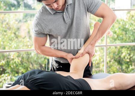 Thérapeute masculin offrant un massage des jambes et du mollet au patient d'athlète sur le lit en clinique, concept de physiothérapie sportive Banque D'Images