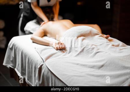 Jeune femme recevant un massage du dos tout en se relaxant au spa salon Banque D'Images