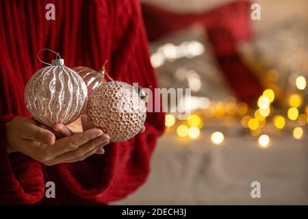 Fond de Noël avec des boules de Noël dans les mains des femmes gros plan avec bokeh sur le fond. Banque D'Images