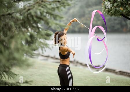 Femme sportive pratiquant la gymnastique rythmique avec un ruban en plein air Banque D'Images