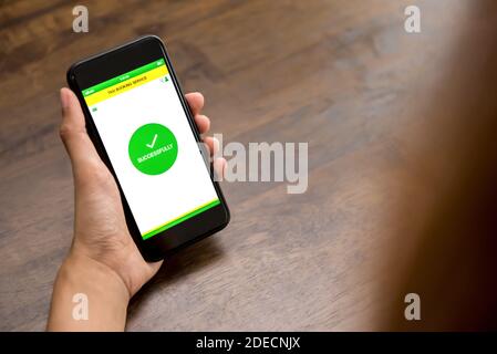 Main tenant le smartphone pour afficher le texte de réservation à l'écran après fin de la réservation de taxi en ligne via l'application Banque D'Images