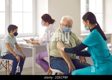 Les infirmières qui donnent des vaccins contre la grippe aux adultes plus âgés et aux enfants pendant campagne de vaccination Banque D'Images