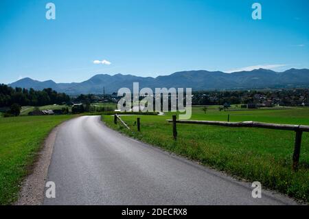 paysage, clôture près de la route descendant la colline à travers la prairie et les champs, jour . Vallée slovène, vue sur la montagne. Banque D'Images