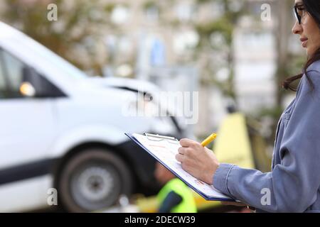 Un agent remplit les documents après un accident de voiture. Banque D'Images